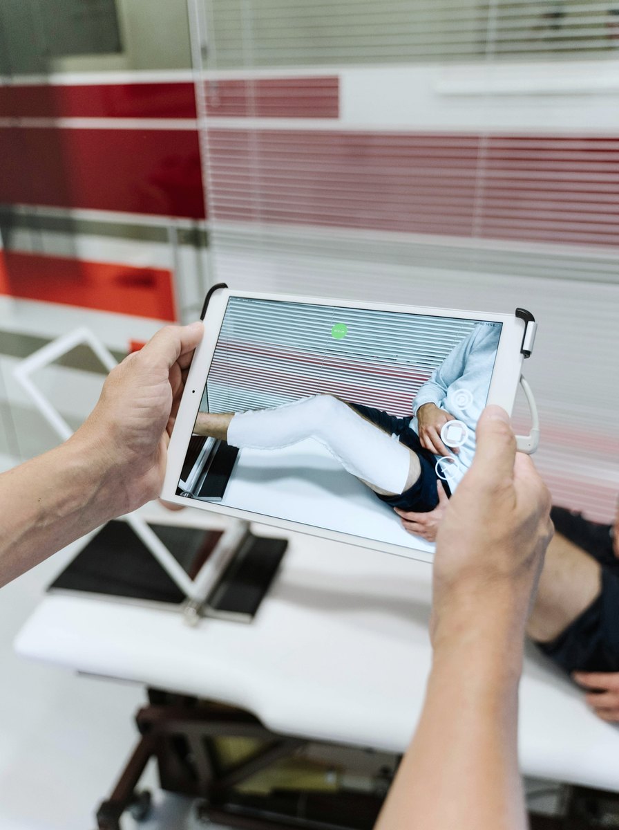 A clinician holding a tablet to capture a 3D scan of a patient's lower leg